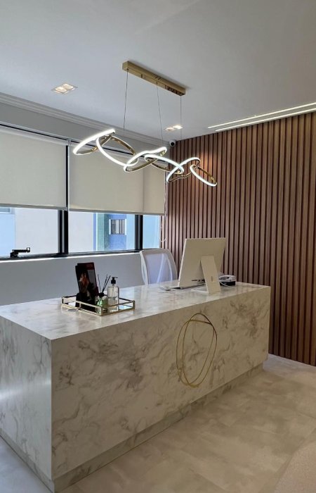Recepção do consultório da Dra. Ívina Andrada, com bancada de mármore e iluminação em pendente