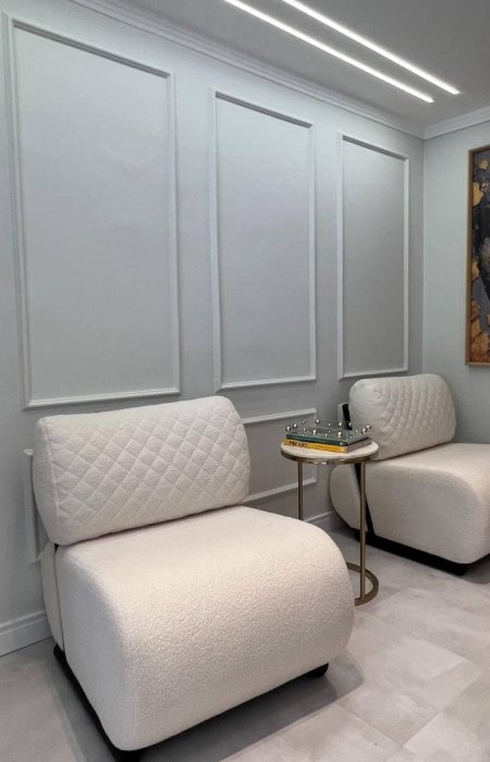 Sala de espera do consultório com poltronas estofadas e mesa de apoio